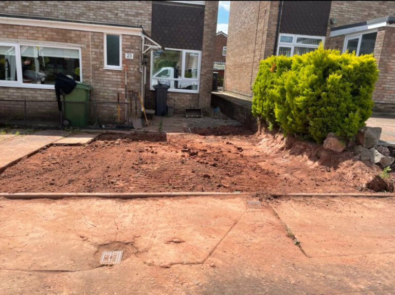 A garden being dug up in front of a house.